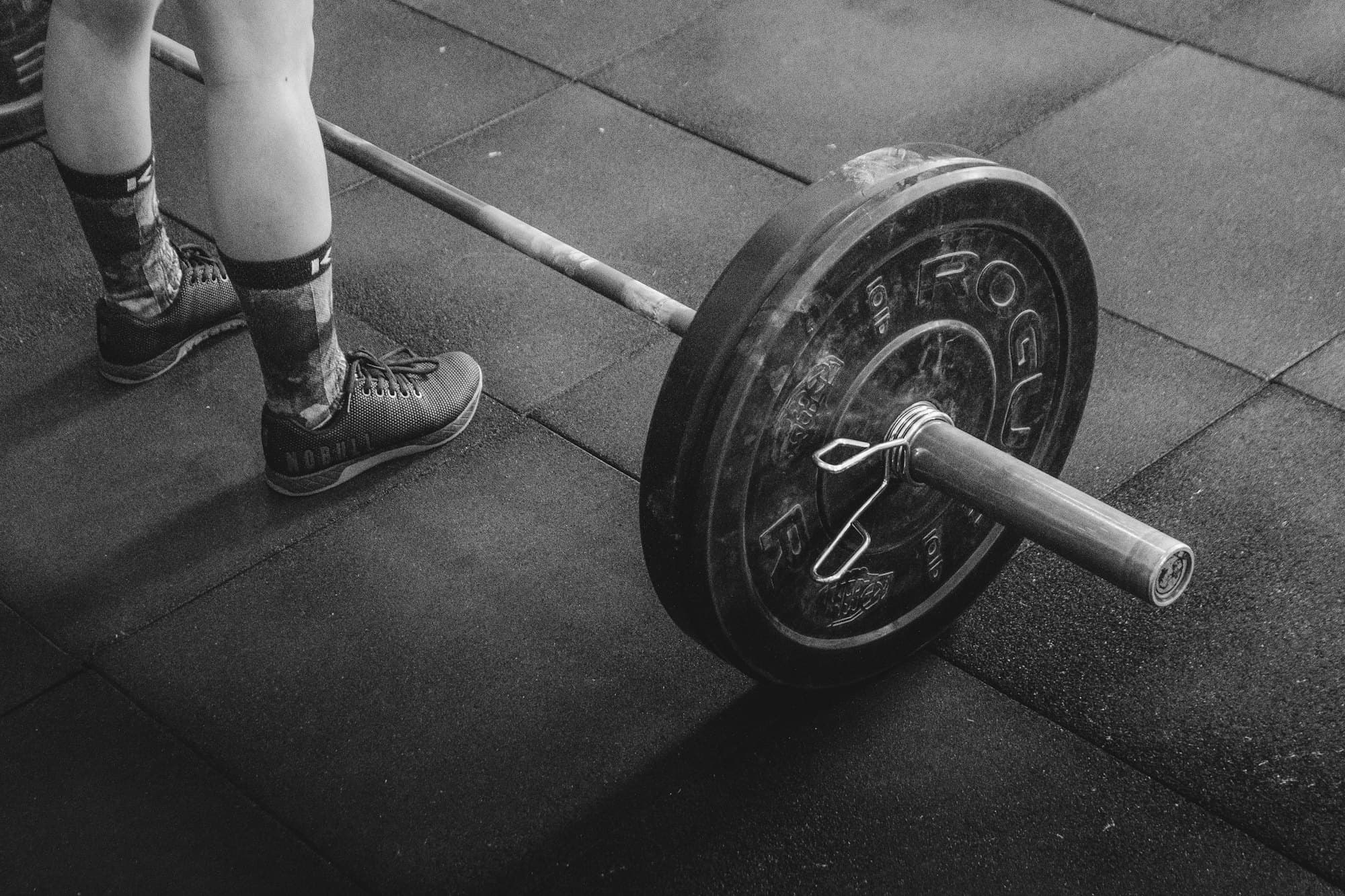 Athlete preparing to lift a loaded barbell in a dark gym
